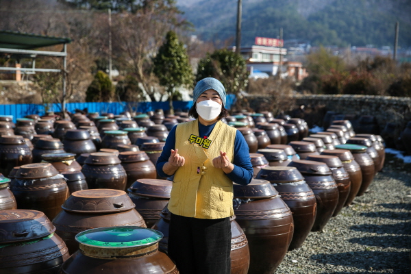 [사진제공=호남백과사전]두미원 김연아 대표가 콩을 삶고 있는 가마솥 앞에서 활짝 웃고 있는 모습이다.