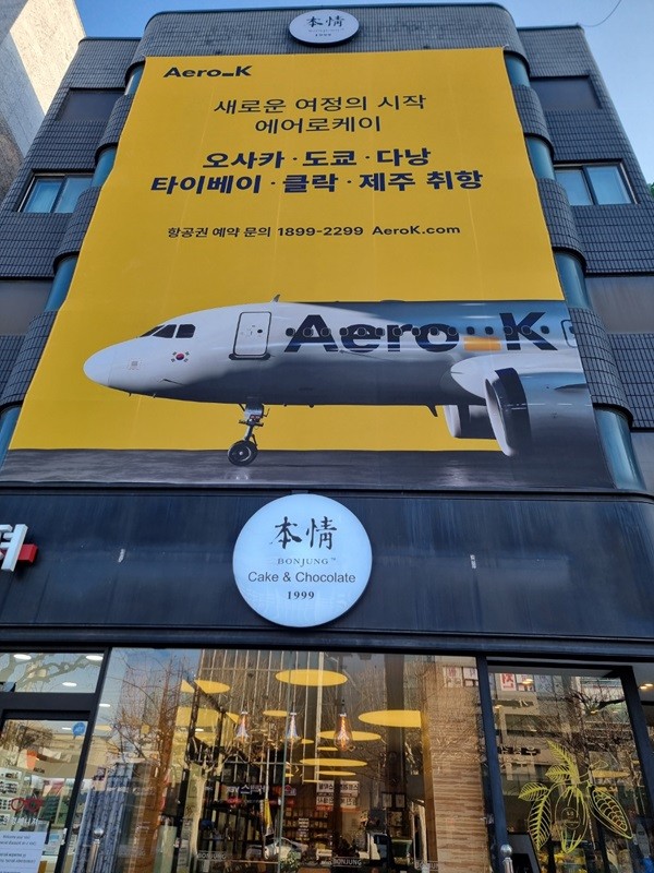 청주본정과 에어로케이 상생마케팅. 충북 청주 본정 초콜릿㈜ 사옥 전면에 에어로케이항공 홍보물이 걸려 있다. /본정 초콜릿
